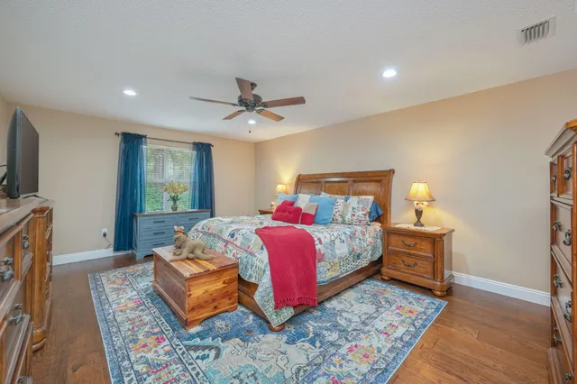 a bedroom with a bed a mirror on dresser and a wooden floor