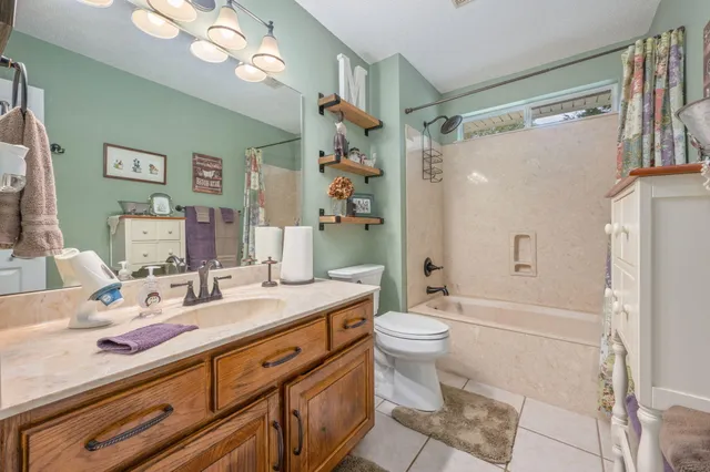 a bathroom with a granite countertop sink a toilet a shower and a mirror