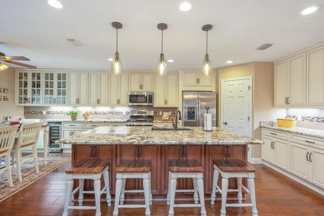 a kitchen with granite countertop kitchen island stainless steel appliances a sink and cabinets