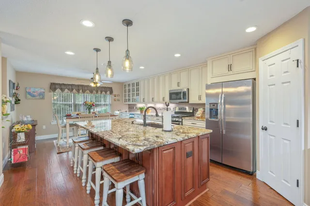 a kitchen with kitchen island granite countertop a table chairs refrigerator and wooden floor
