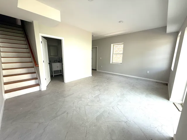 a view of an empty room with stairs and a window