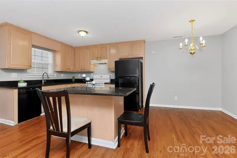 a kitchen with stainless steel appliances granite countertop a stove top oven a refrigerator a sink and a dining table with wooden floor