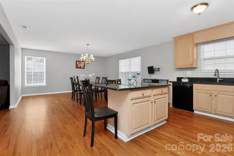 a kitchen with granite countertop a stove a sink dishwasher a dining table and chairs with wooden floor