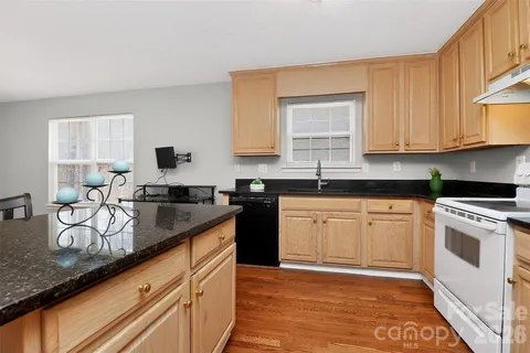 a kitchen with granite countertop stainless steel appliances a sink window and cabinets