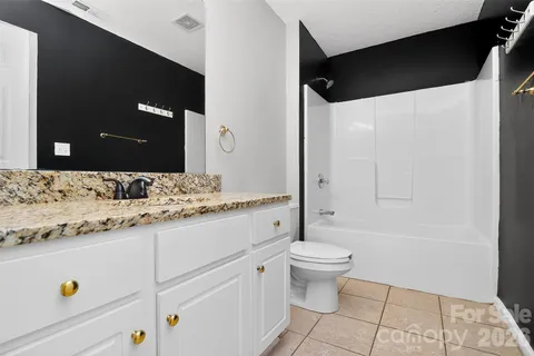 a bathroom with a granite countertop sink a toilet and a mirror