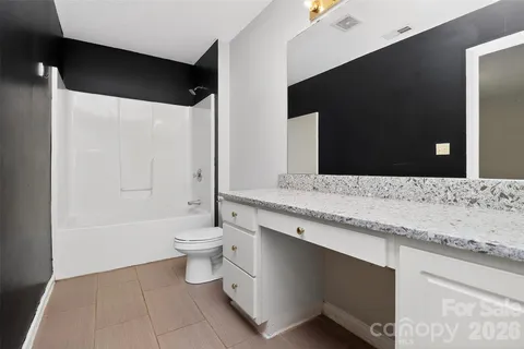 a bathroom with a granite countertop sink a toilet and a bathtub
