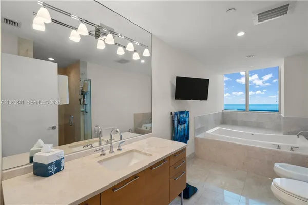 a bathroom with a sink a large mirror and a bathtub