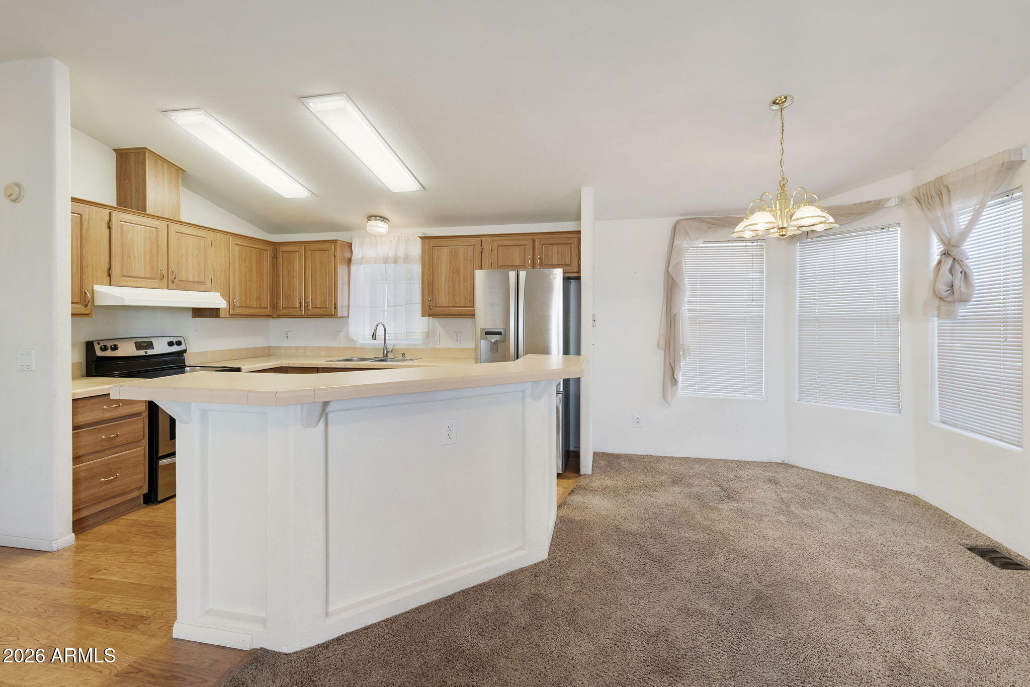 3700 South Tomahawk Road, Unit 73 Apache Junction, AZ 85119 - Photo 28 of 49 a kitchen with kitchen island granite countertop a stove a sink a refrigerator and white cabinets with wooden floor