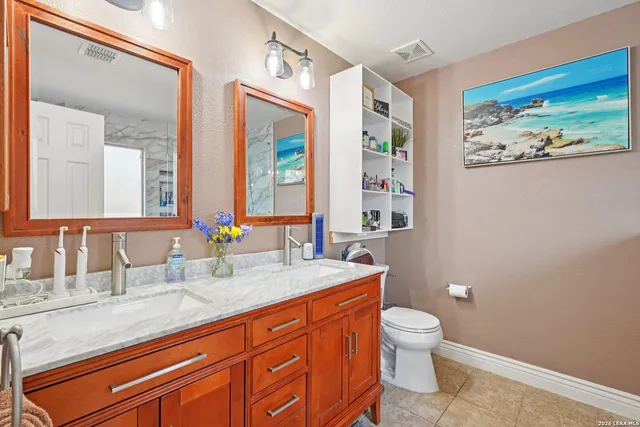 a bathroom with a granite countertop sink toilet and painting on the wall