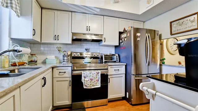 a kitchen with stainless steel appliances granite countertop a refrigerator sink and stove