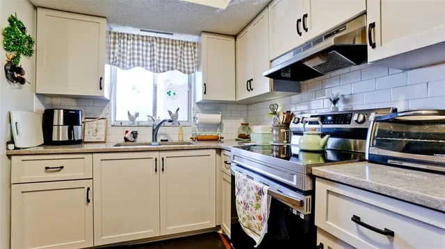 a kitchen with a sink a stove cabinets and a window