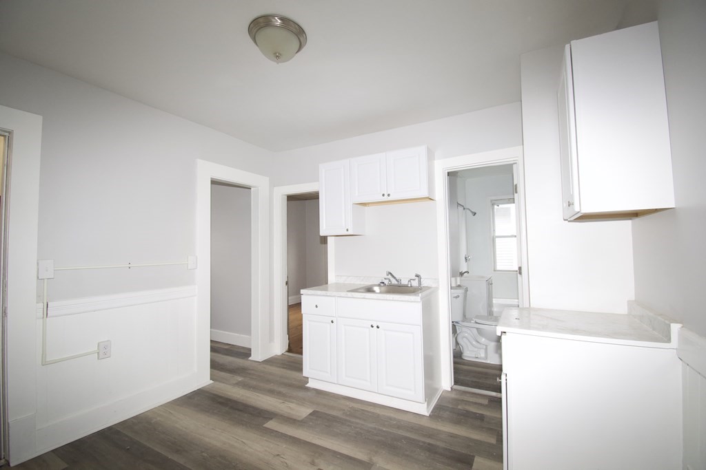 72 Malden Street Springfield, MA 01108 - Photo 16 of 25 a view of a kitchen with white cabinets and wooden floor