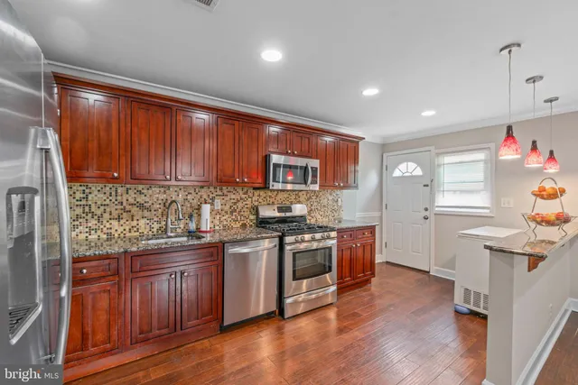a kitchen with granite countertop wooden cabinets stainless steel appliances and a wooden floor