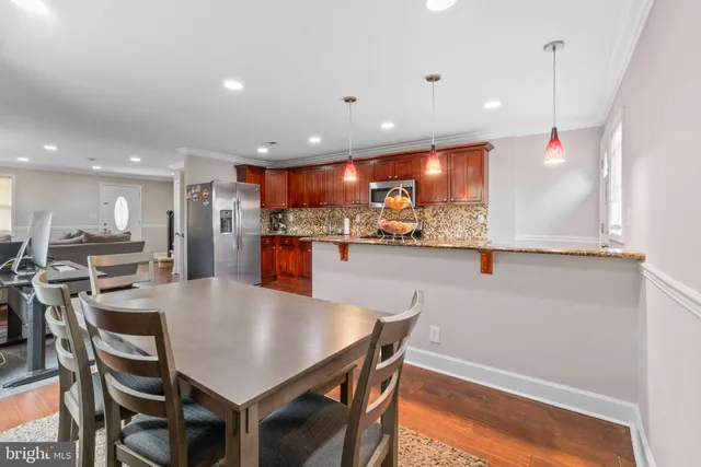 a kitchen with stainless steel appliances a dining table chairs and stove