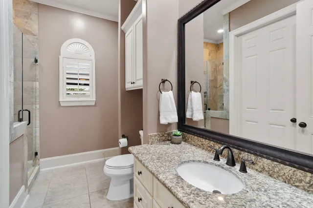 a bathroom with a granite countertop toilet a sink and a mirror