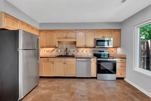 a kitchen with granite countertop white cabinets and stainless steel appliances