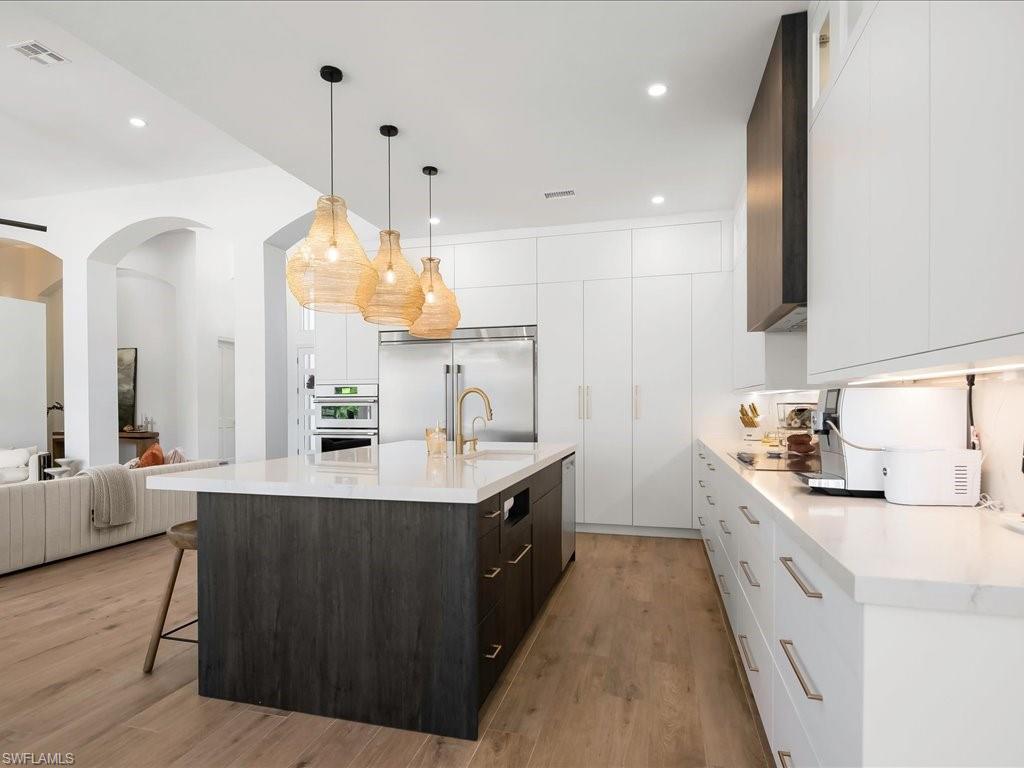 2115 Imperial Golf Course Boulevard Naples, FL 34110 - Photo 12 of 50 a large white kitchen with a large island oven a sink a counter space and stainless steel appliances