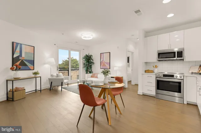 a living room with furniture a rug kitchen view and a large window