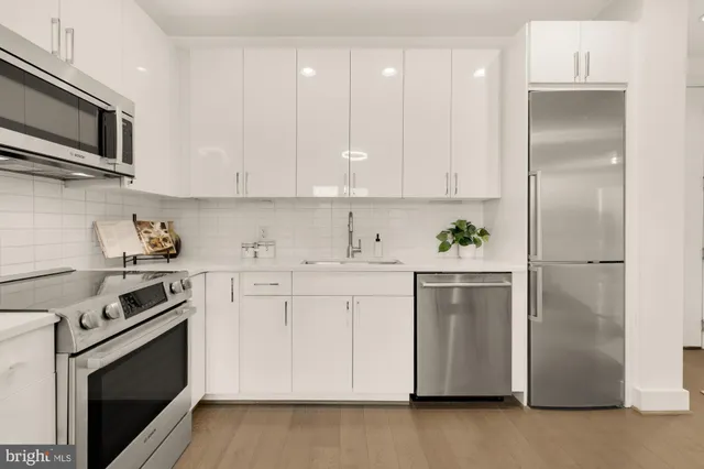 a kitchen with cabinets stainless steel appliances and wooden floor