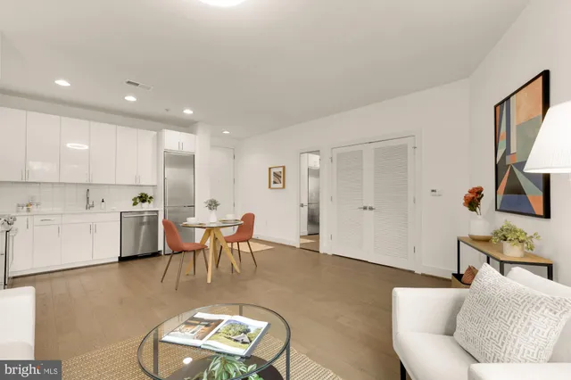 a living room with furniture a dining table and kitchen view with wooden floor