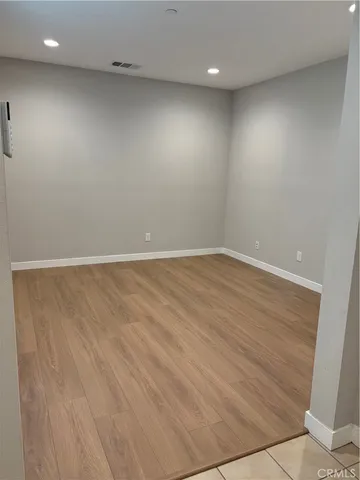an empty room with wooden floor and fan