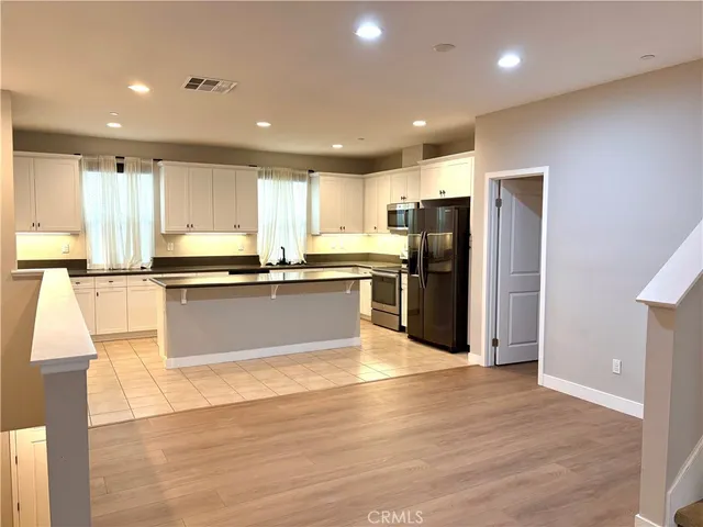 a large kitchen with stainless steel appliances granite countertop a stove a refrigerator and a sink