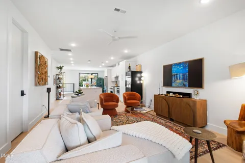 a living room with furniture a flat screen tv and kitchen view