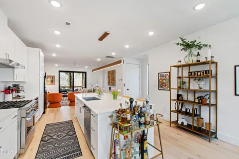 a kitchen with stainless steel appliances a refrigerator a stove a sink dishwasher a dining table and chairs with wooden floor