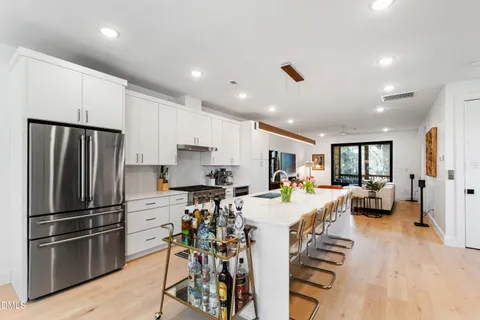 a large kitchen with lots of counter space a sink dishwasher and a stove with wooden floor