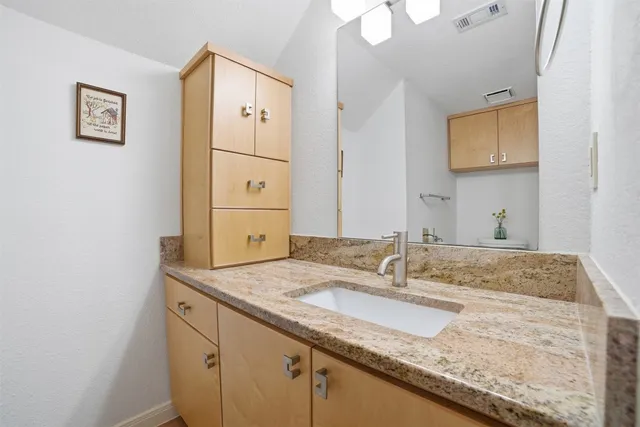 a bathroom with a granite countertop sink and a mirror