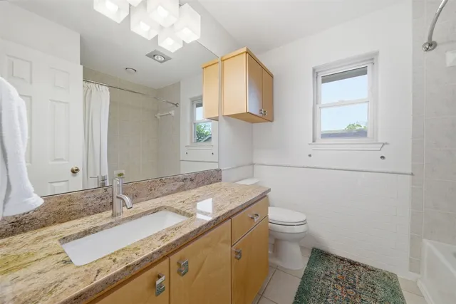 a bathroom with a granite countertop sink a toilet and a mirror