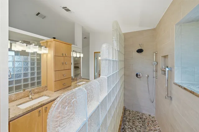 a bathroom with a granite countertop sink a mirror and shower