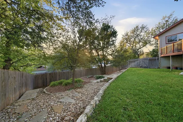 a view of a yard with a large tree and wooden fence