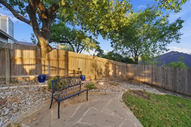 a view of a backyard with a large tree and wooden fence
