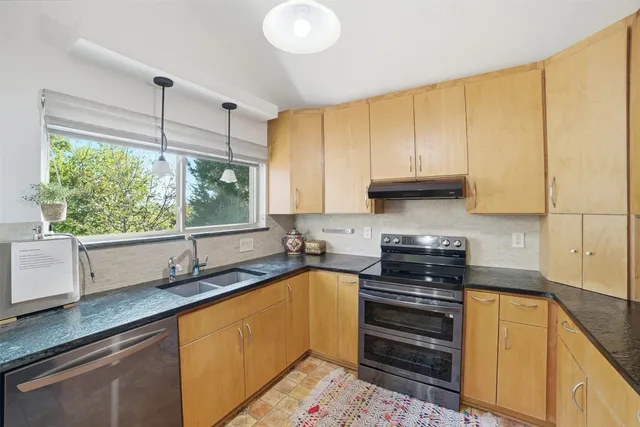 a kitchen with kitchen island granite countertop a sink a counter space appliances and cabinets
