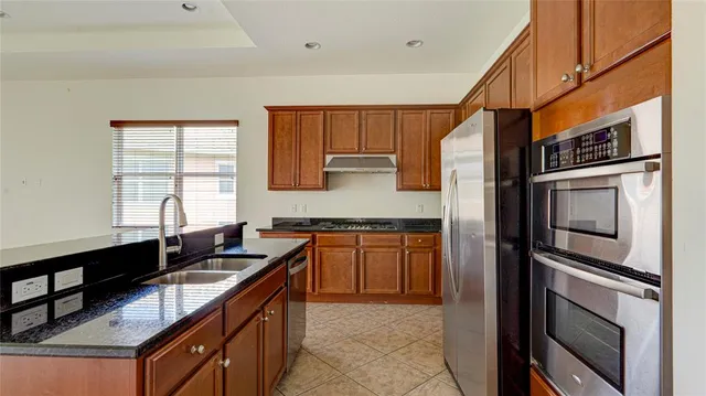 a kitchen with stainless steel appliances granite countertop a refrigerator and a stove top oven