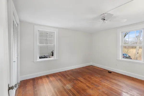 an empty room with wooden floor and windows