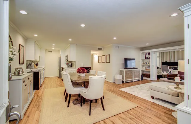 a living room with stainless steel appliances furniture a flat screen tv and a kitchen view