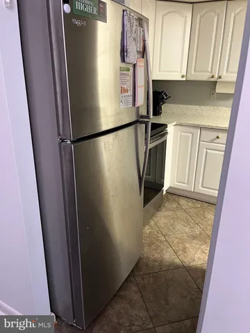 a view of a refrigerator in kitchen and an empty room