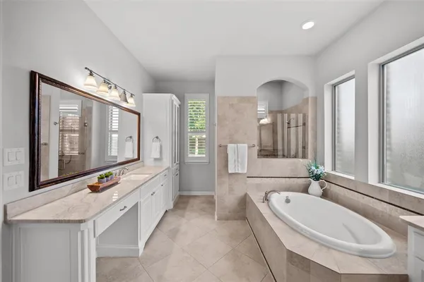 a spacious bathroom with a double vanity sink a mirror and a bathtub