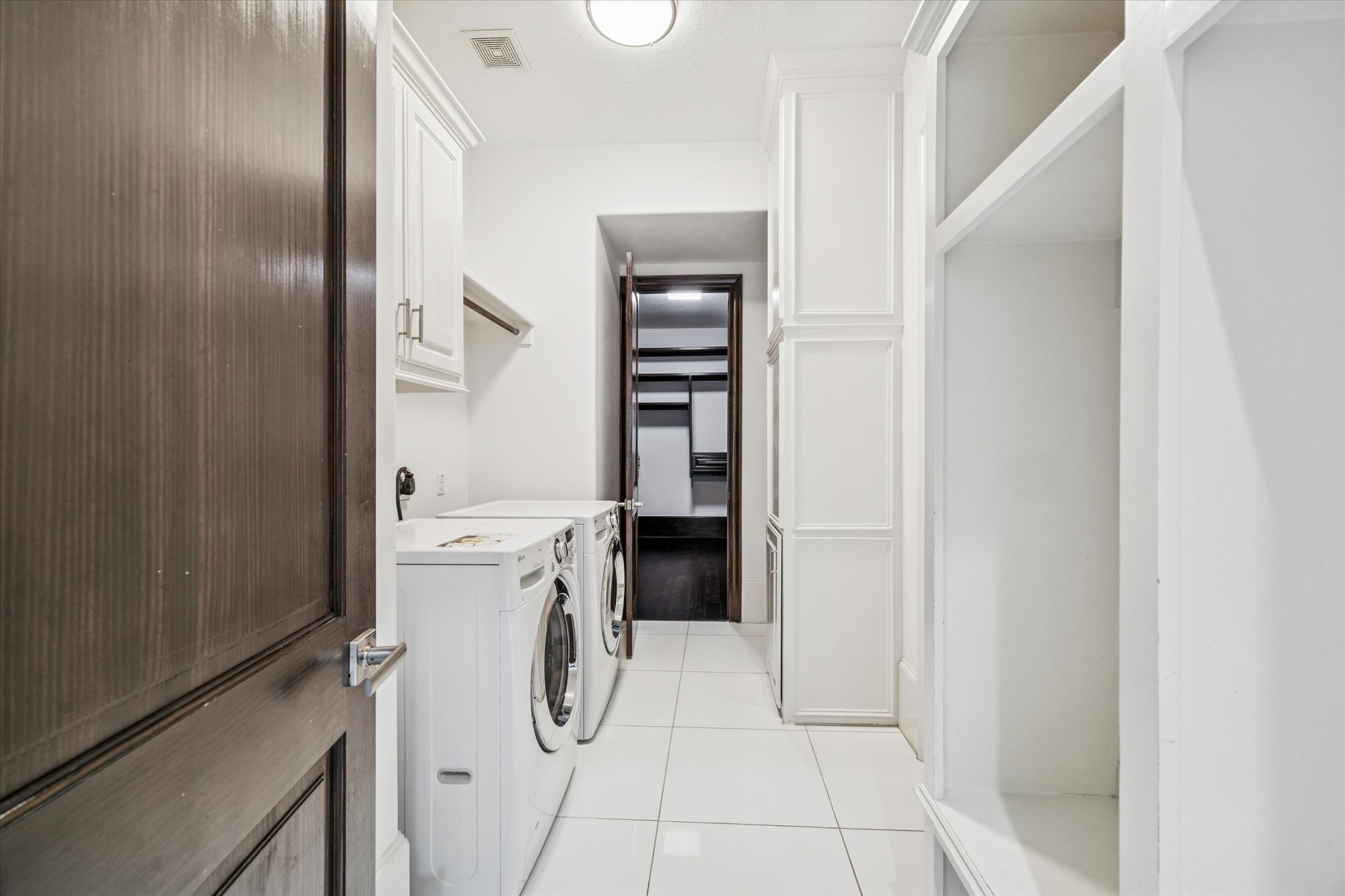 3942 Charleston Street Houston, TX 77021 - Photo 16 of 34 Built-in cabinetry and open shelving keep the utility space clean and intentional. Full-size washer and dryer sit on polished tile floors, tucked neatly between the primary bath and closet for an efficient daily flow.