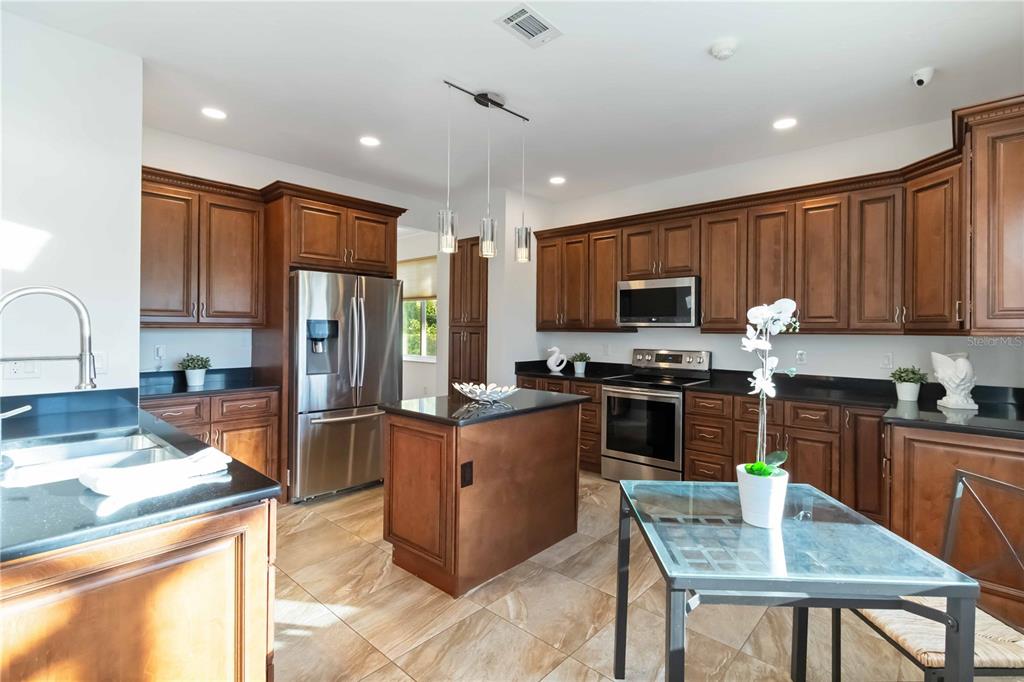 4223 Balmoral Way Sarasota, FL 34238 - Photo 13 of 72 a kitchen with stainless steel appliances granite countertop a stove top oven a sink dishwasher a dining table and chairs with wooden floor