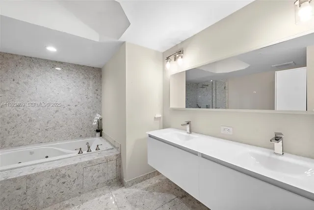 a bathroom with a bathtub a mirror a sink and vanity