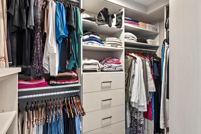 a view of walk in closet with clothes and shoes