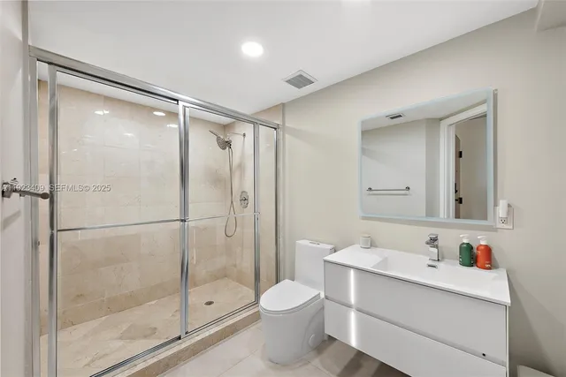 a bathroom with a shower sink vanity and toilet
