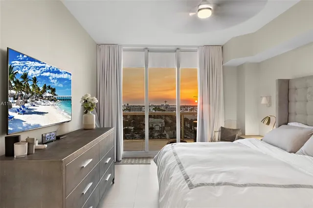 a bedroom with a large bed and a flat tv screen on dresser