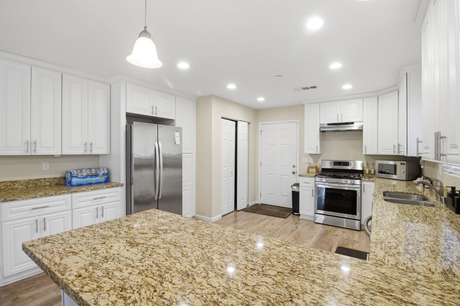 243 Angelus Street Turlock, CA 95380 - Photo 11 of 26 a kitchen with stainless steel appliances granite countertop a stove top oven a sink and a refrigerator