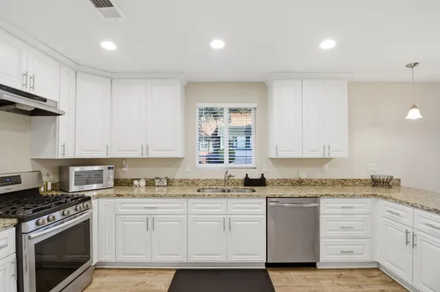 a kitchen with granite countertop a stove sink and cabinets
