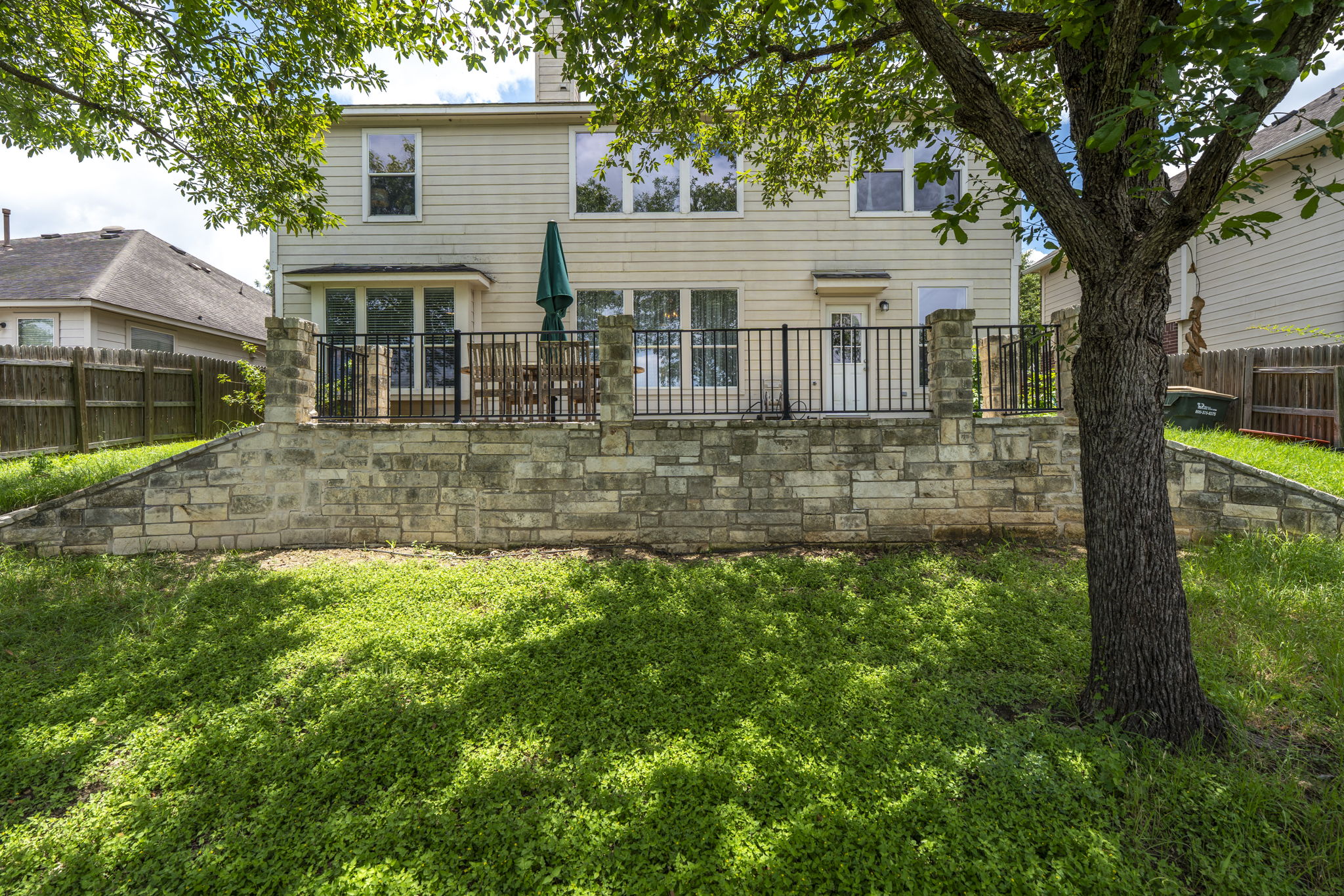 454 Fall Circle Kyle, TX 78640 - Photo 35 of 39 A spacious backyard with a stone retaining wall and elevated patio.