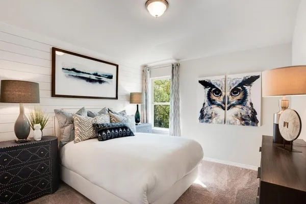 a bedroom with a bed and painting on the wall